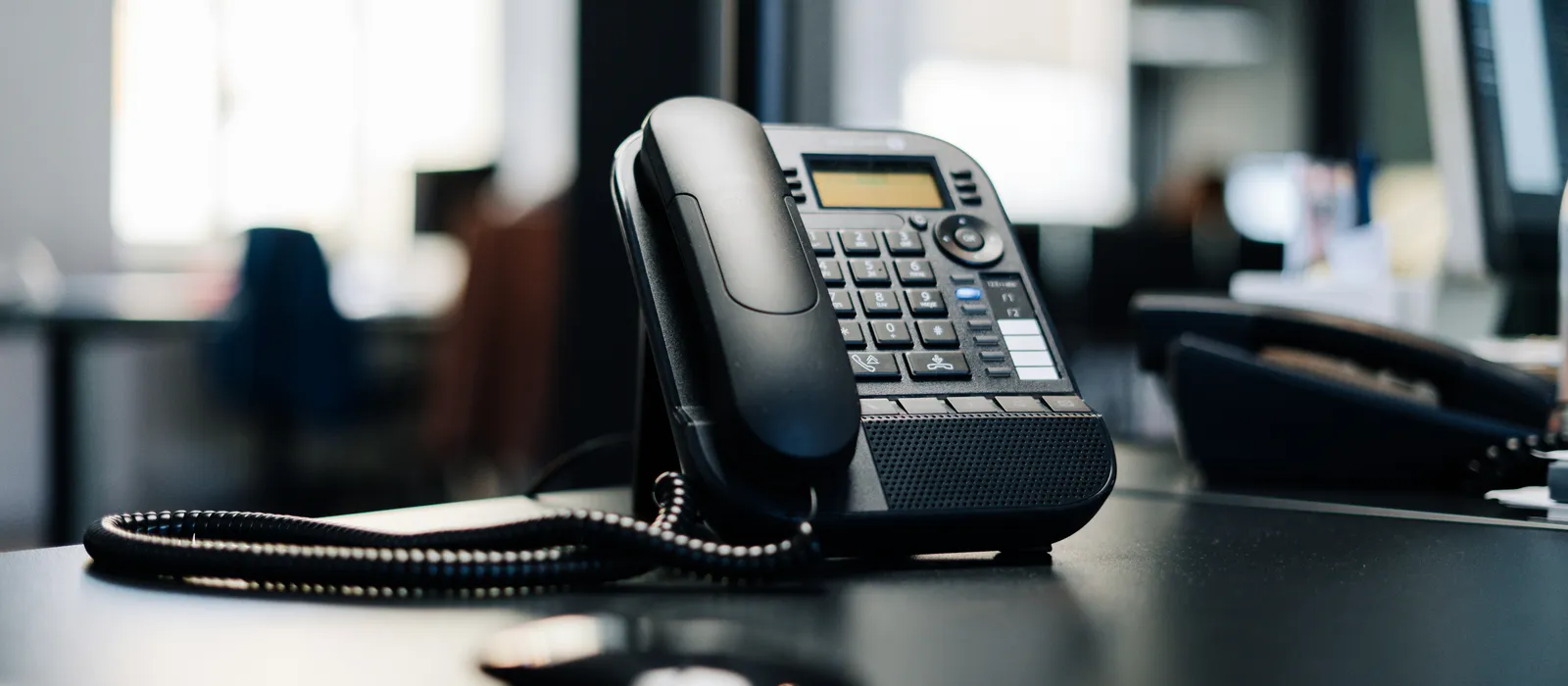 Téléphone fixe de bureau, au premier plan d'un open space